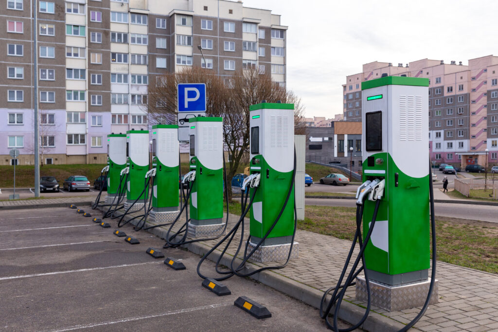 Bilparkering med laddstationer nära ett flervåningshus. Grön energianvändning, snabbladdningsstationer för urbana elfordon.