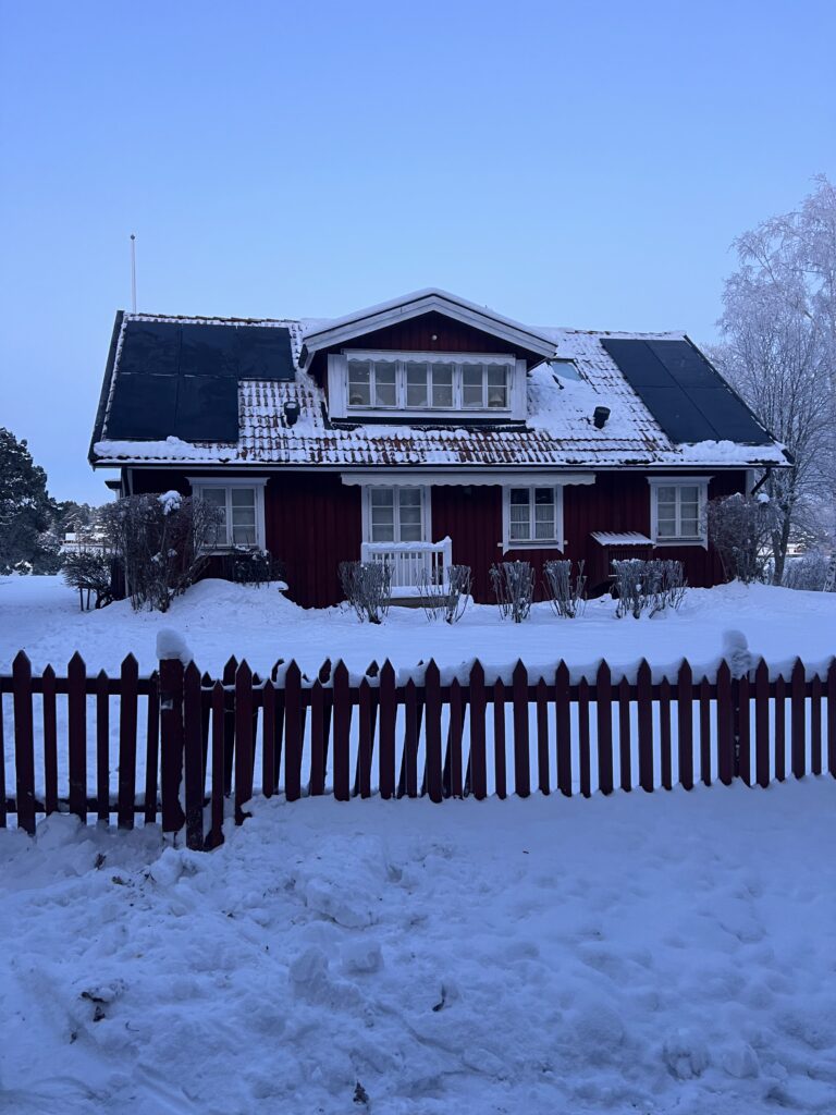 Svensk villa med solpaneler på taket under vintertid.